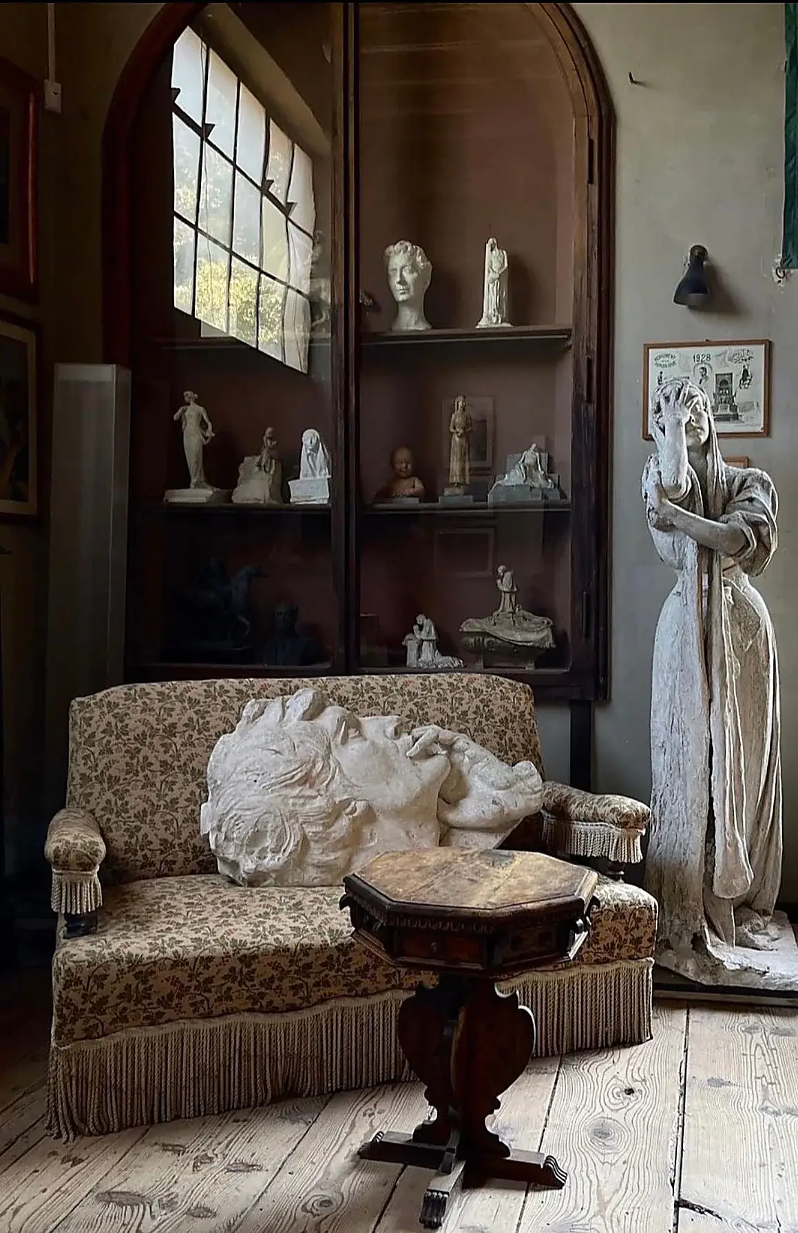 Artist’s atelier with plaster casts, antique furniture and a tall arched window