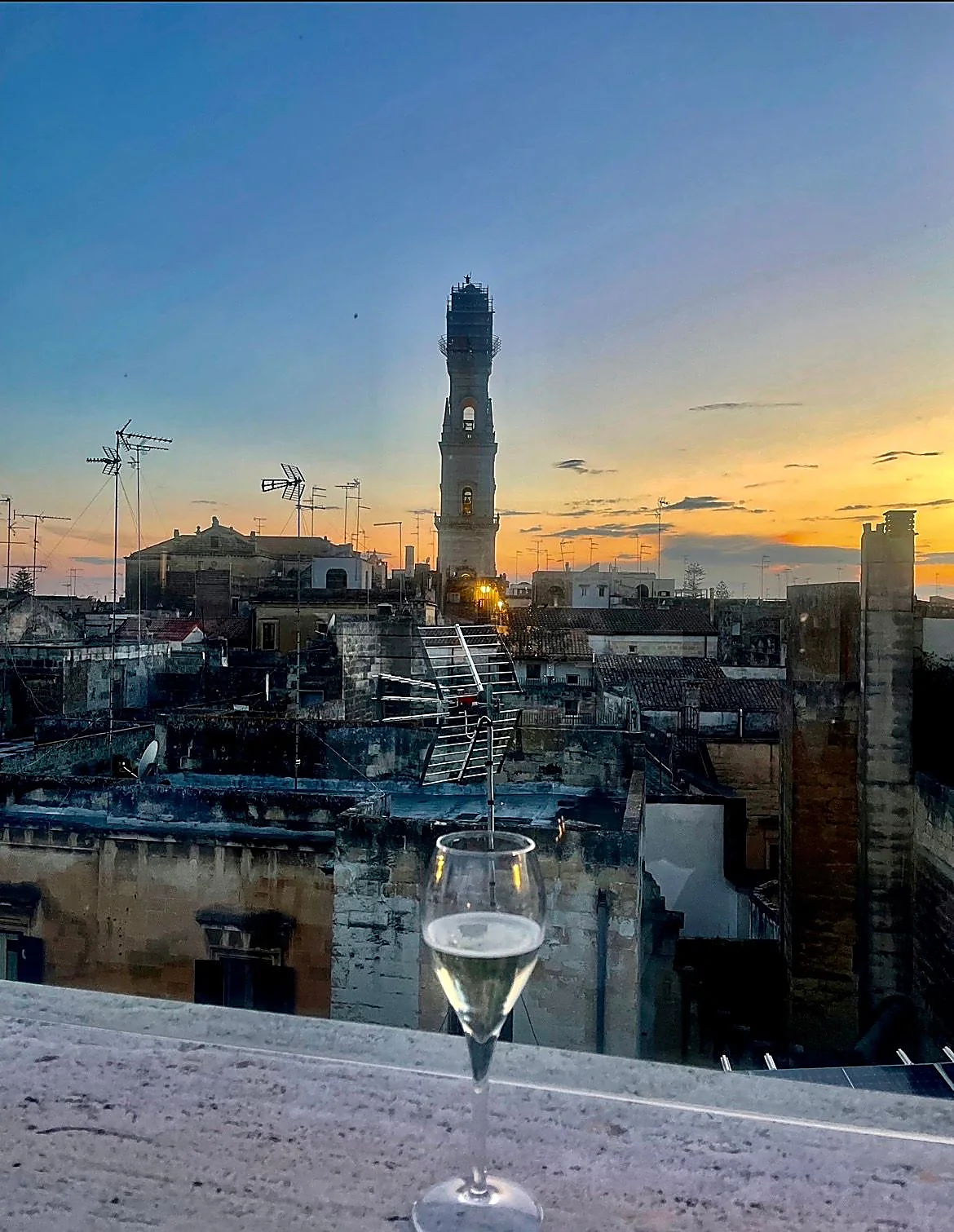 A glass of white wine on a terrace overlooking the rooftops of Florence at sunset